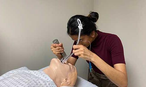 a woman practicing on a patient mannequin.